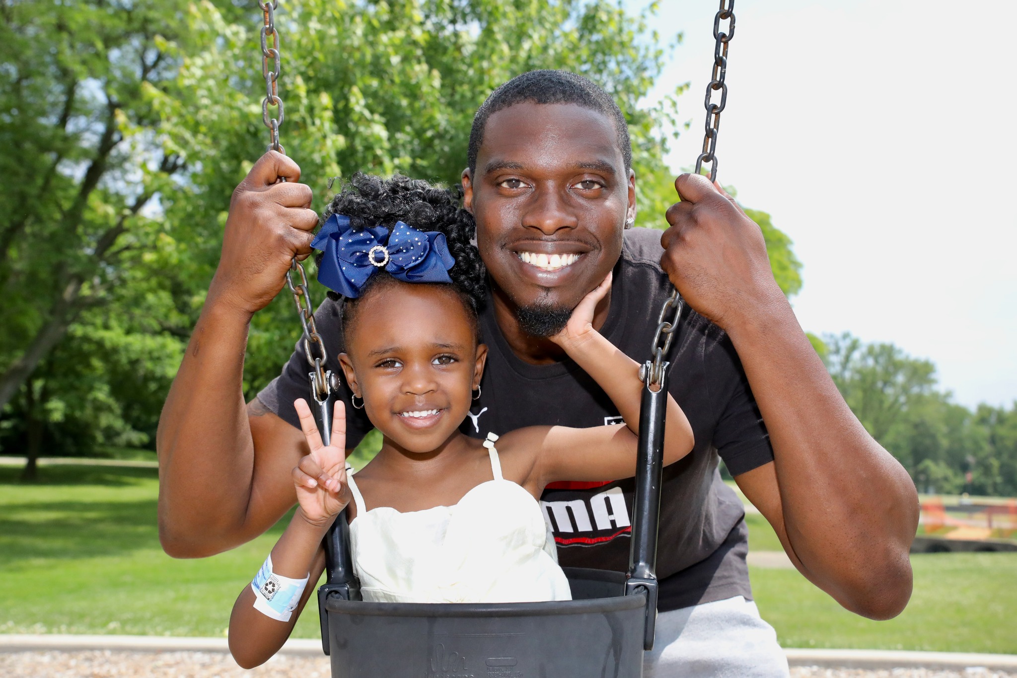 Father and daughter on swings at Family Field Day 2025